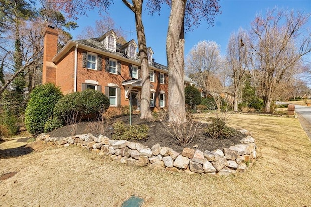 view of front facade with a chimney and brick siding