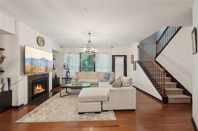 4430 Cedar Bridge Walk, Suwanee, GA 30024 - living room featuring a fireplace with flush hearth, dark wood-style floors, baseboards, a chandelier, and stairway
