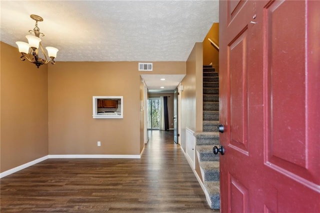 entryway featuring an inviting chandelier, dark hardwood / wood-style floors, and a textured ceiling