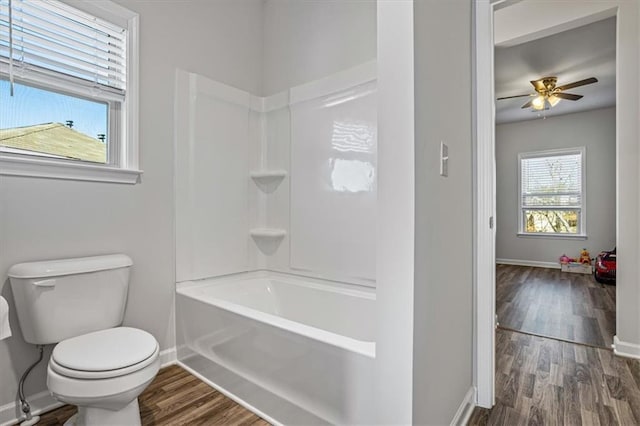 bathroom with hardwood / wood-style flooring, ceiling fan, toilet, and bathing tub / shower combination