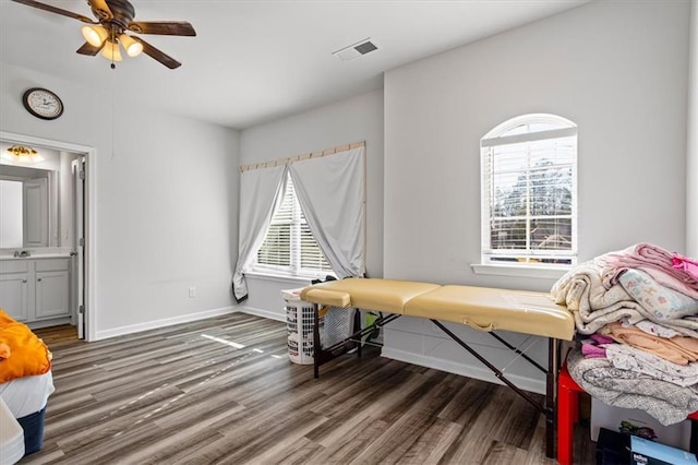 bedroom featuring dark hardwood / wood-style flooring, ensuite bath, ceiling fan, and sink