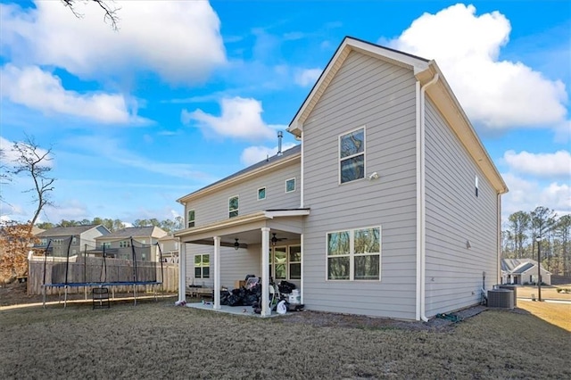 back of property with ceiling fan, central AC unit, a patio, a trampoline, and a lawn