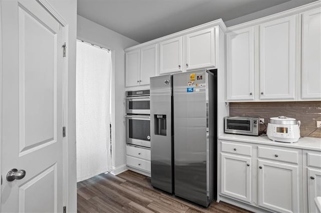 kitchen with appliances with stainless steel finishes, backsplash, dark hardwood / wood-style floors, and white cabinetry