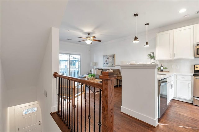 kitchen featuring white cabinets, kitchen peninsula, dark wood-type flooring, and stainless steel appliances