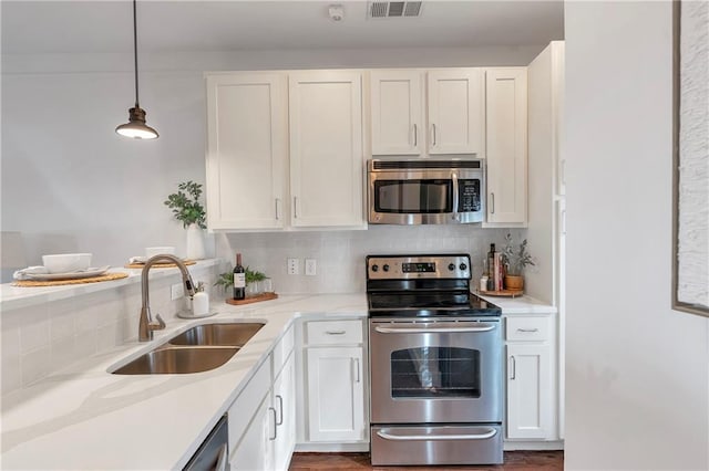 kitchen featuring stainless steel appliances, white cabinetry, hanging light fixtures, and sink