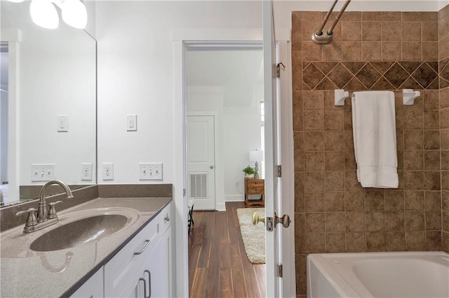 bathroom featuring hardwood / wood-style floors, vanity, and tiled shower / bath combo