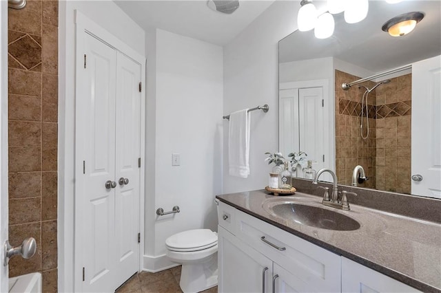 bathroom with toilet, tile patterned flooring, vanity, and tiled shower