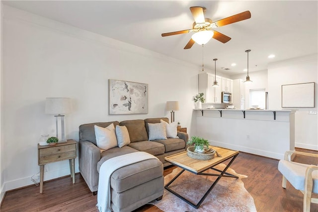 living room featuring ornamental molding, ceiling fan, and dark wood-type flooring