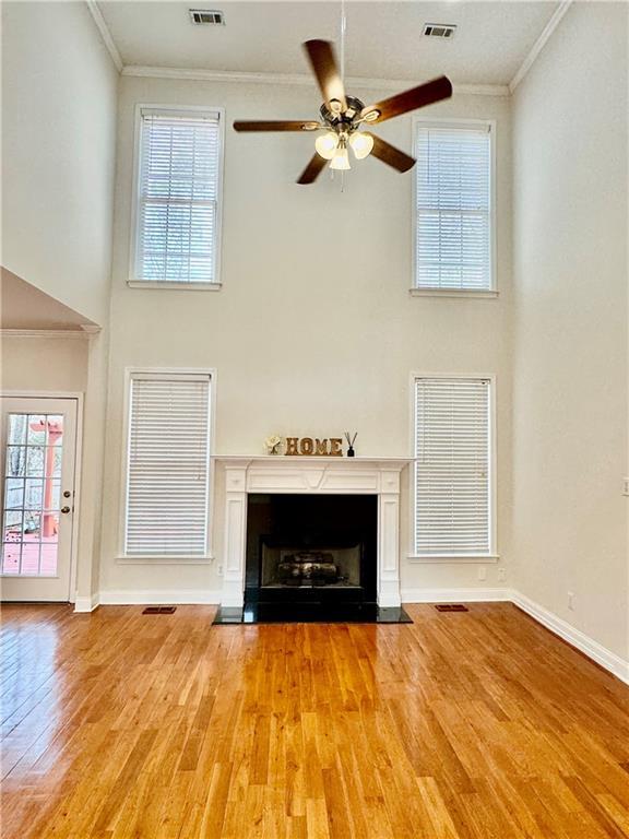 unfurnished living room with light hardwood / wood-style flooring, a high ceiling, and ornamental molding