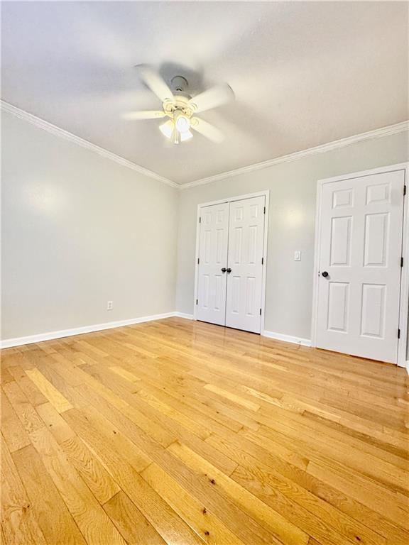 unfurnished bedroom with ceiling fan, light wood-type flooring, and ornamental molding