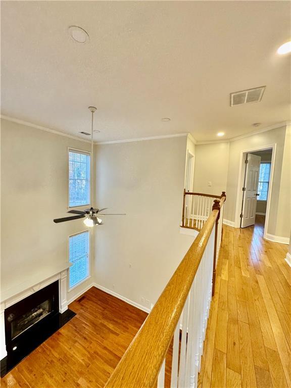 corridor with light wood-type flooring and crown molding