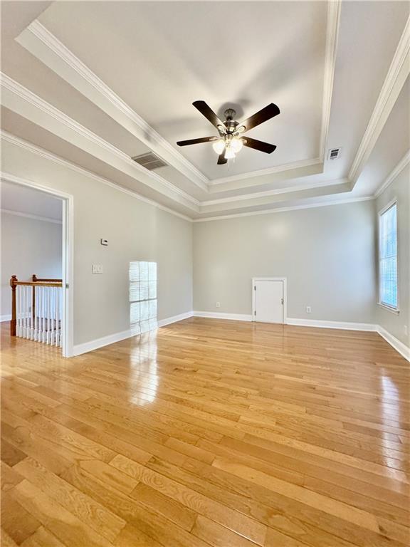 unfurnished room featuring a raised ceiling, light hardwood / wood-style flooring, and ceiling fan