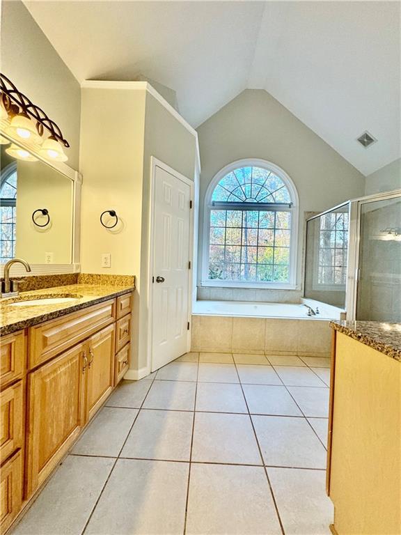 bathroom with vanity, vaulted ceiling, tile patterned floors, and separate shower and tub