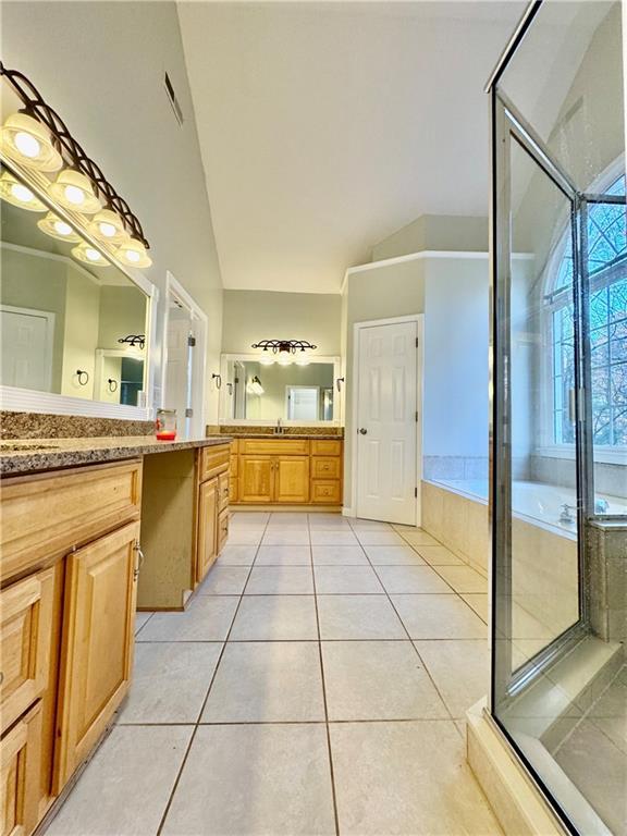 bathroom with tile patterned floors, vanity, lofted ceiling, and shower with separate bathtub