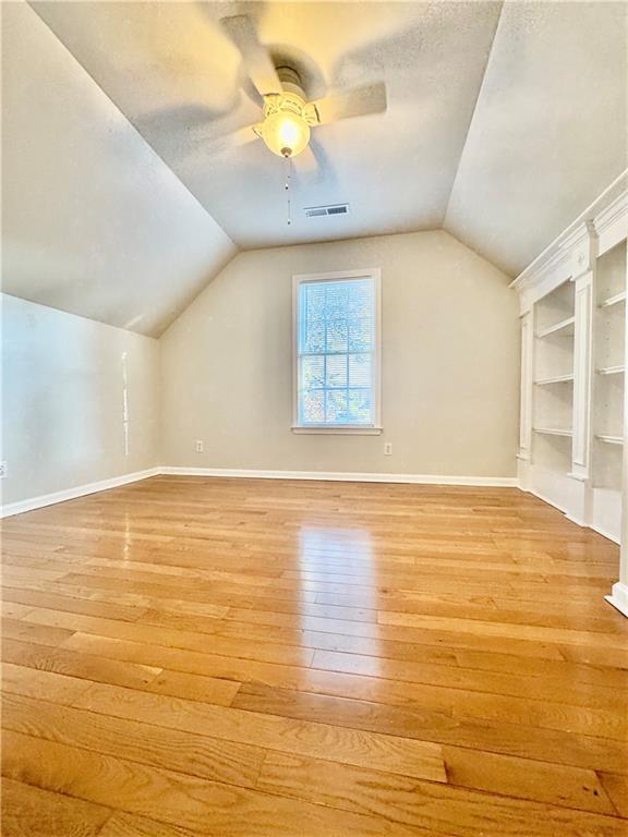 additional living space with ceiling fan, light hardwood / wood-style flooring, and vaulted ceiling