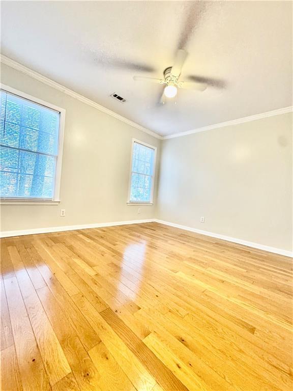 empty room featuring wood-type flooring, ceiling fan, and ornamental molding