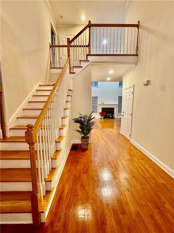 staircase with hardwood / wood-style floors and ornamental molding