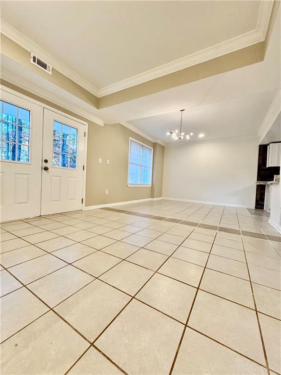 tiled entrance foyer featuring an inviting chandelier and ornamental molding