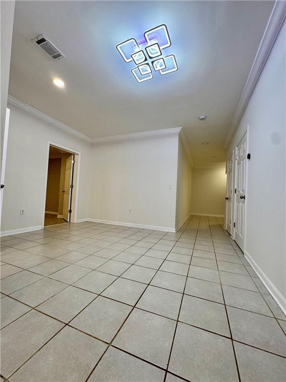 tiled empty room featuring crown molding