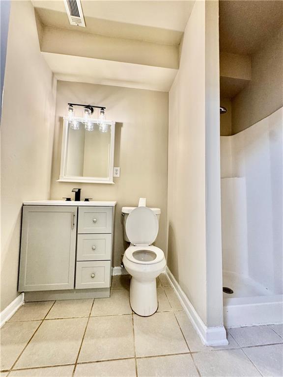 bathroom featuring toilet, tile patterned flooring, vanity, and walk in shower