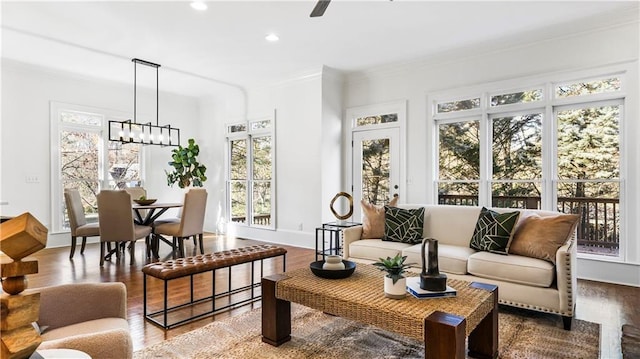 living area featuring crown molding, baseboards, recessed lighting, wood finished floors, and a notable chandelier