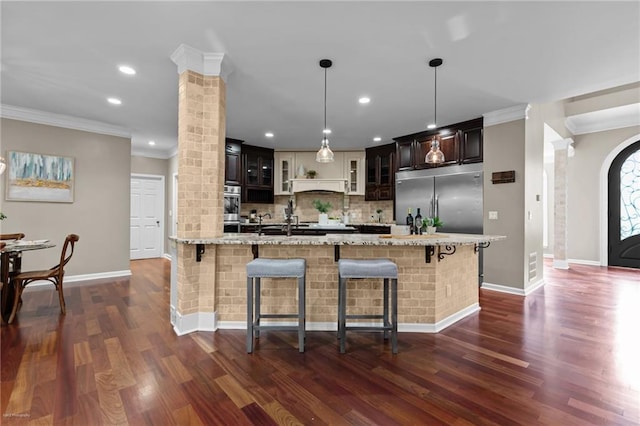 2990 Hearthstone Dr, Cumming, GA 30041 - kitchen with decorative columns, crown molding, a breakfast bar, backsplash, and stainless steel appliances