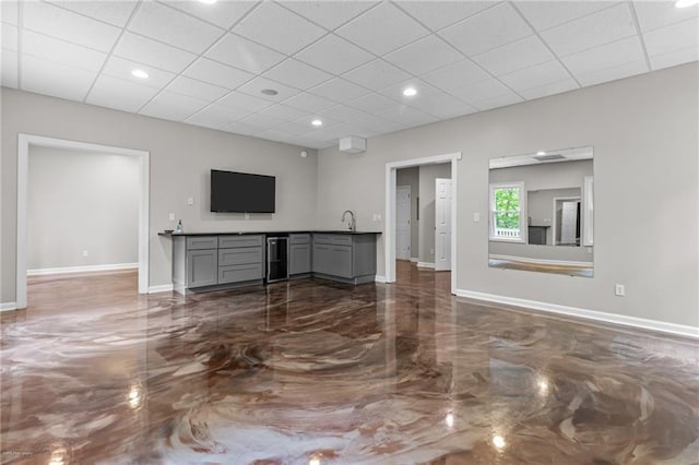 2990 Hearthstone Dr, Cumming, GA 30041 - unfurnished living room with a paneled ceiling, baseboards, wine cooler, dark marble finish flooring, and bar