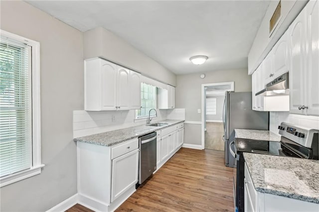 kitchen with white cabinets, appliances with stainless steel finishes, tasteful backsplash, and light stone countertops