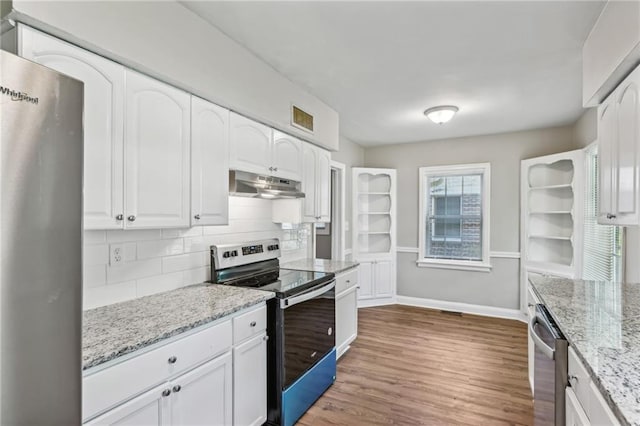 kitchen featuring white cabinetry, light stone countertops, decorative backsplash, appliances with stainless steel finishes, and hardwood / wood-style flooring