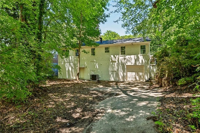 rear view of property with central AC and a garage