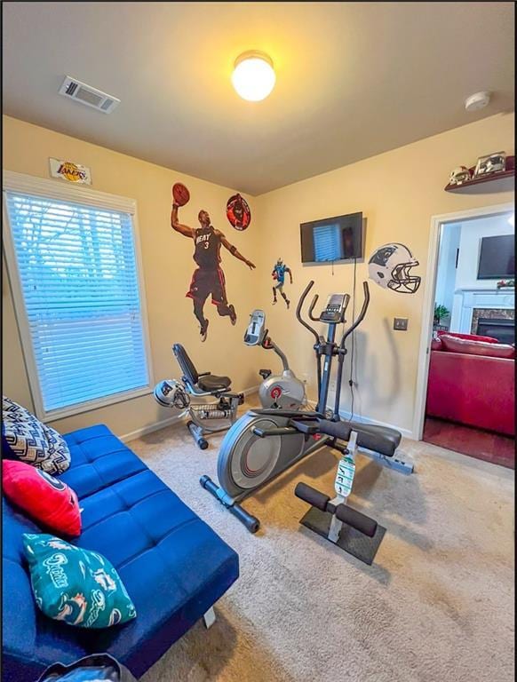 exercise area with a fireplace and carpet