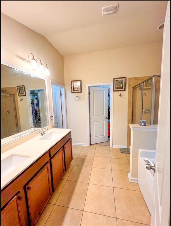 bathroom featuring lofted ceiling, tile patterned flooring, vanity, and an enclosed shower