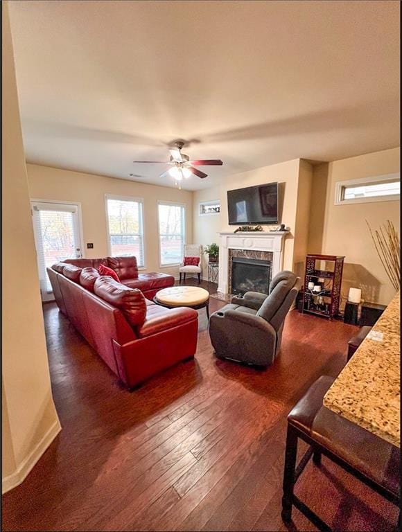 living room with dark hardwood / wood-style floors, ceiling fan, and a premium fireplace