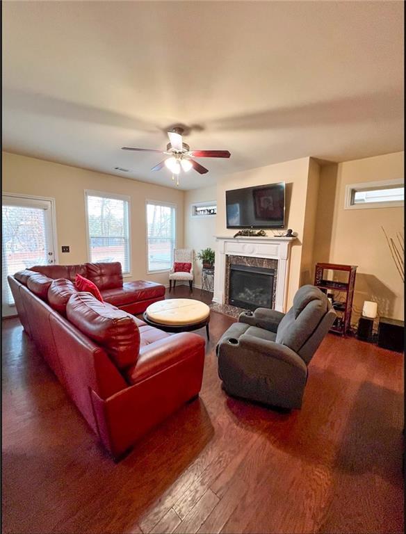 living room with hardwood / wood-style floors, ceiling fan, and a premium fireplace