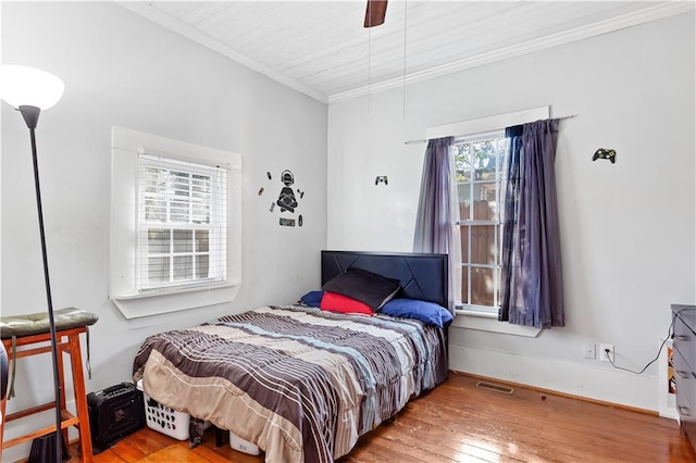 bedroom with ceiling fan, visible vents, wood-type flooring, and ornamental molding