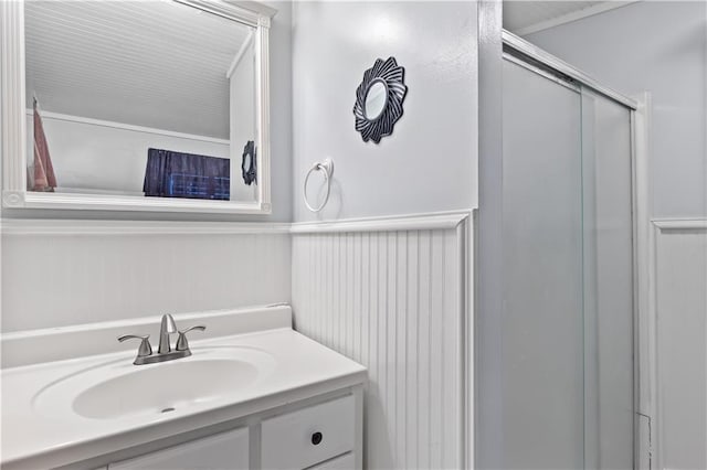 full bathroom with a shower with door, a wainscoted wall, and vanity