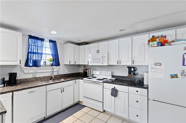 kitchen featuring dark countertops, light tile patterned floors, white appliances, white cabinetry, and a sink