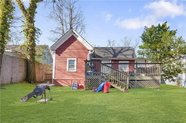 rear view of house with a wooden deck, a lawn, and a fenced backyard