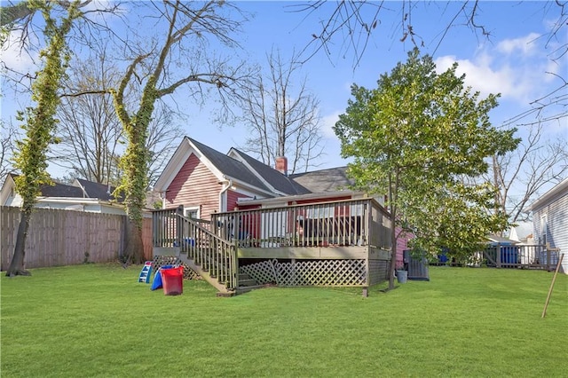 rear view of property featuring a wooden deck, a yard, a chimney, and fence