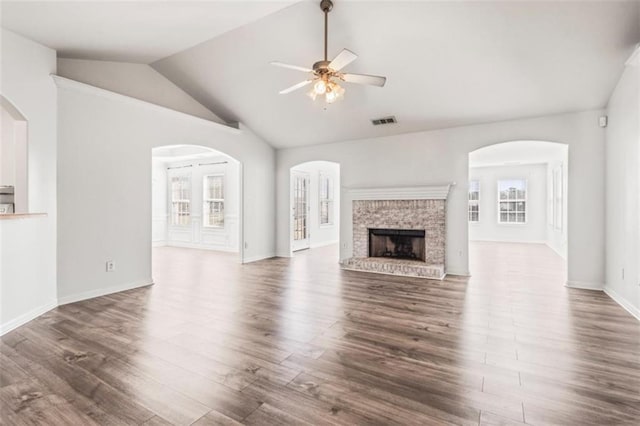 unfurnished living room featuring visible vents, ceiling fan, dark wood-type flooring, vaulted ceiling, and a brick fireplace