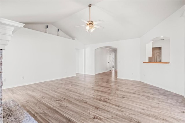 unfurnished living room with arched walkways, vaulted ceiling, ceiling fan, and light wood-style flooring