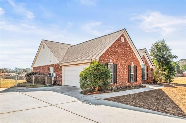 view of home's exterior with a garage, driveway, brick siding, and fence