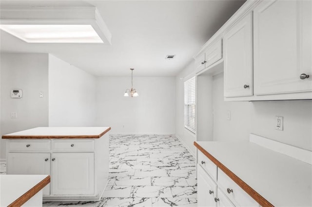 kitchen with visible vents, white cabinetry, marble finish floor, light countertops, and hanging light fixtures