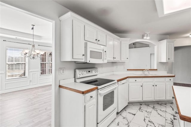 kitchen with light countertops, white appliances, a sink, and white cabinetry