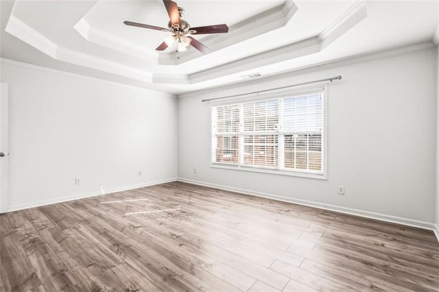 unfurnished room with wood finished floors, a raised ceiling, and baseboards