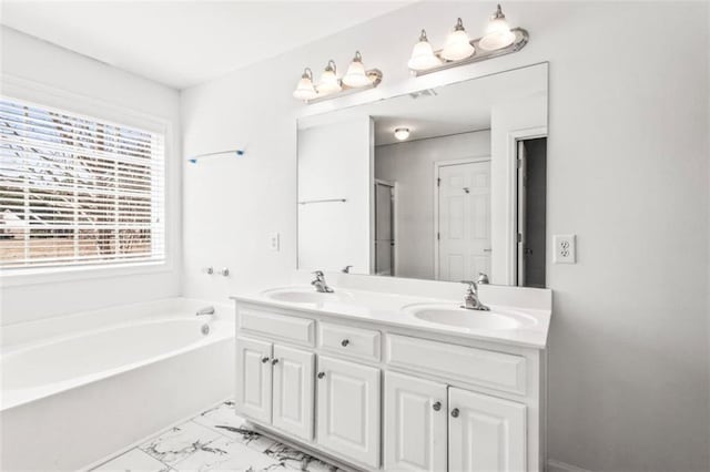 bathroom with marble finish floor, a sink, a bath, and double vanity