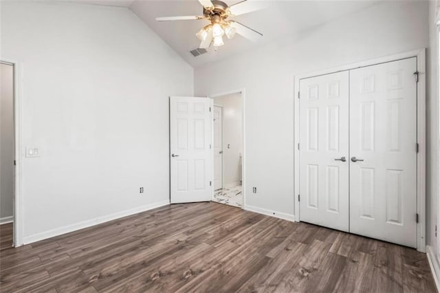 unfurnished bedroom featuring baseboards, visible vents, dark wood-style floors, vaulted ceiling, and a closet