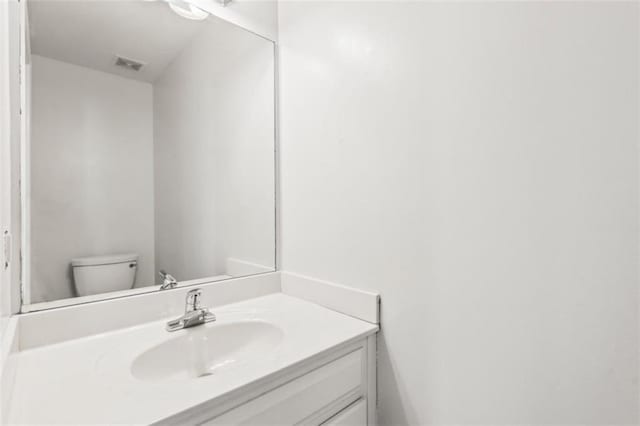 bathroom with toilet, visible vents, and vanity