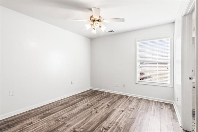 spare room featuring ceiling fan, wood finished floors, visible vents, and baseboards