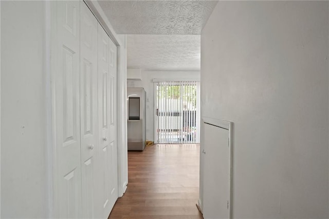 corridor featuring a textured ceiling and hardwood / wood-style flooring